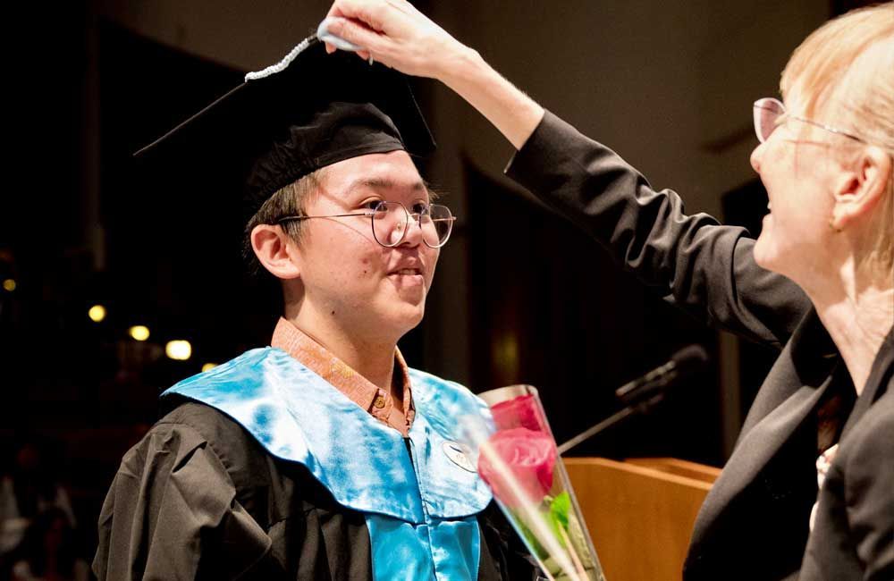A woman is wiping the cap of a graduate