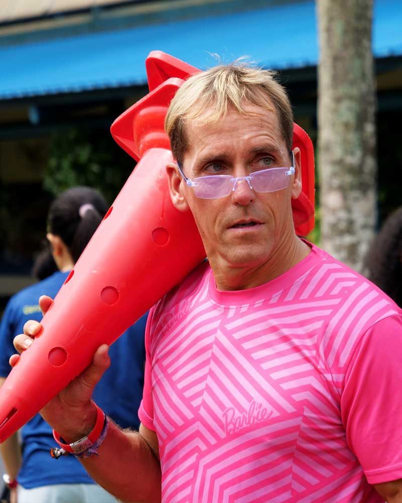 A man in a pink shirt is holding a red cone over his shoulder