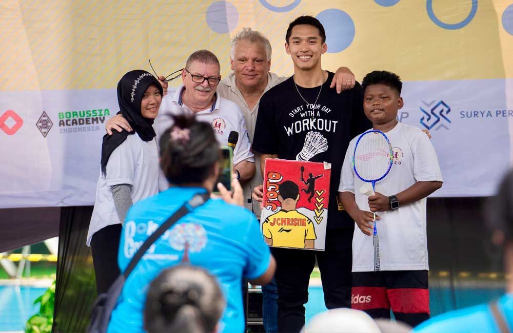 A group of people are posing for a picture while holding badminton rackets.
