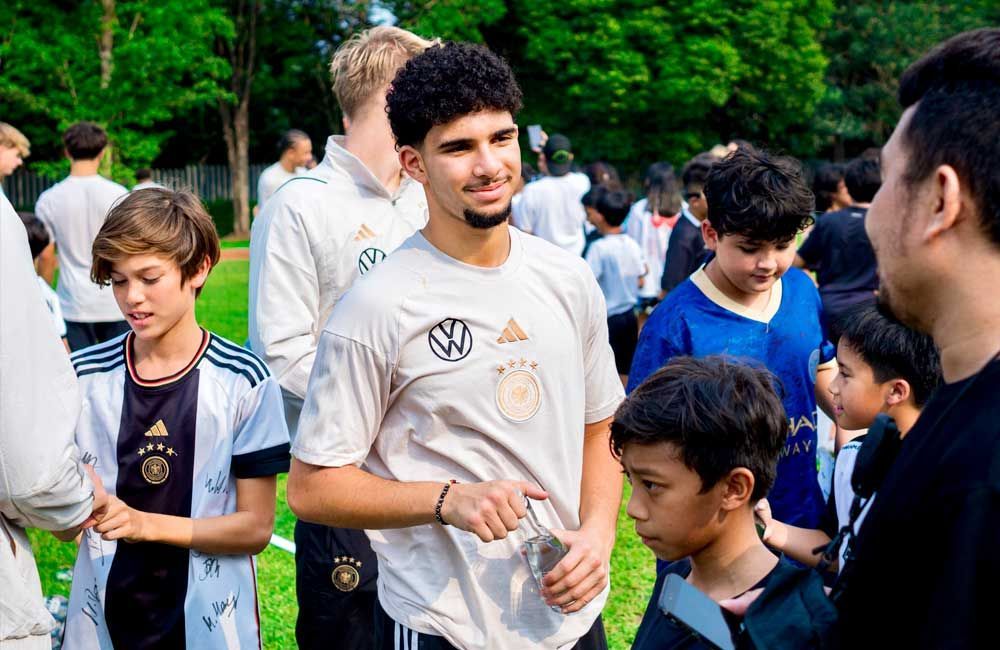 A group of young men are standing in a field talking to each other.