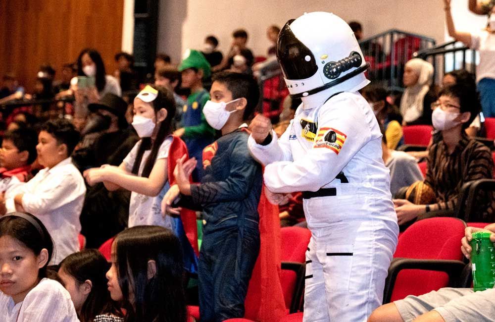 A group of children dressed in costumes are standing in front of a crowd.