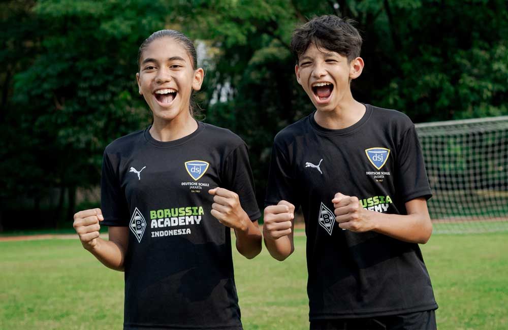 A boy and a girl are standing next to each other on a soccer field.