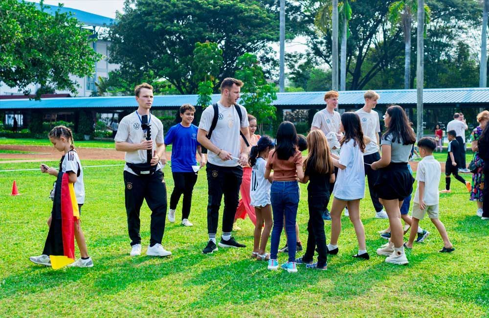 A group of people are standing on top of a lush green field.