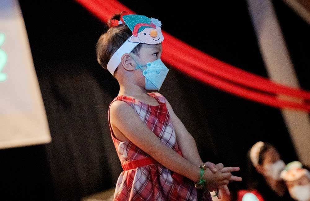 A little girl wearing a mask and a snowman headband