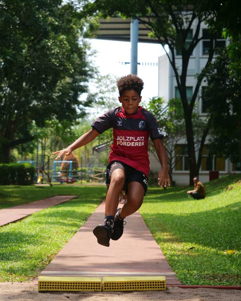 A young boy in a red shirt is jumping in the air