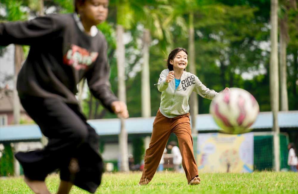 Two young girls are playing with a soccer ball in a park.