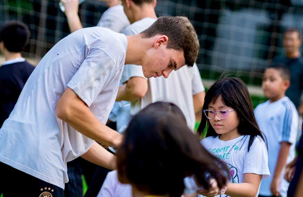 A young man is helping a young girl with her hair.
