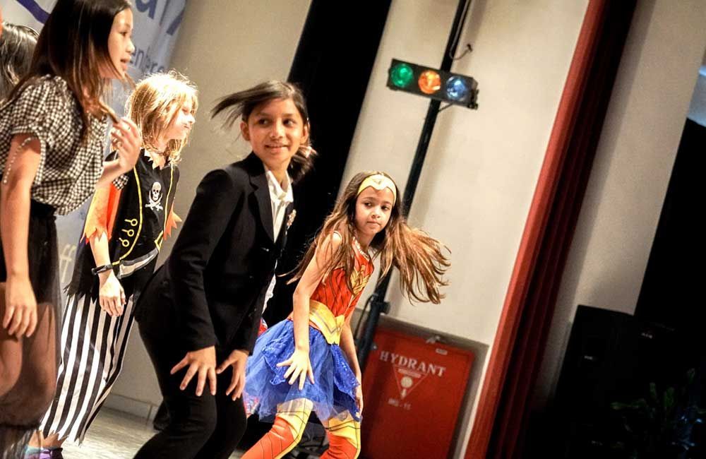 A group of young girls dressed in costumes are dancing on a stage.