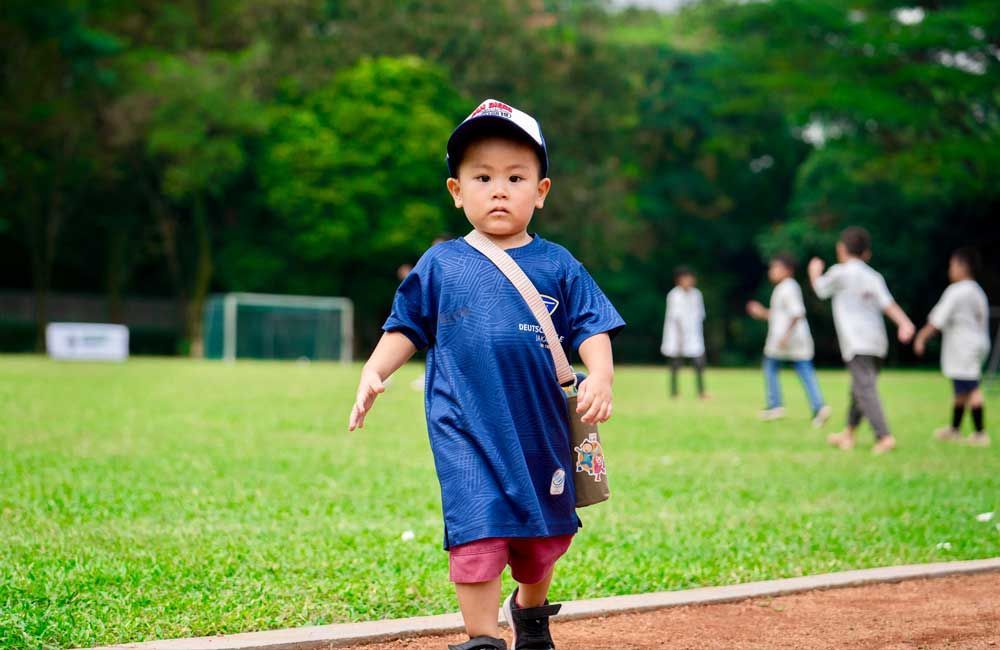 A little boy is walking on a track in a field.