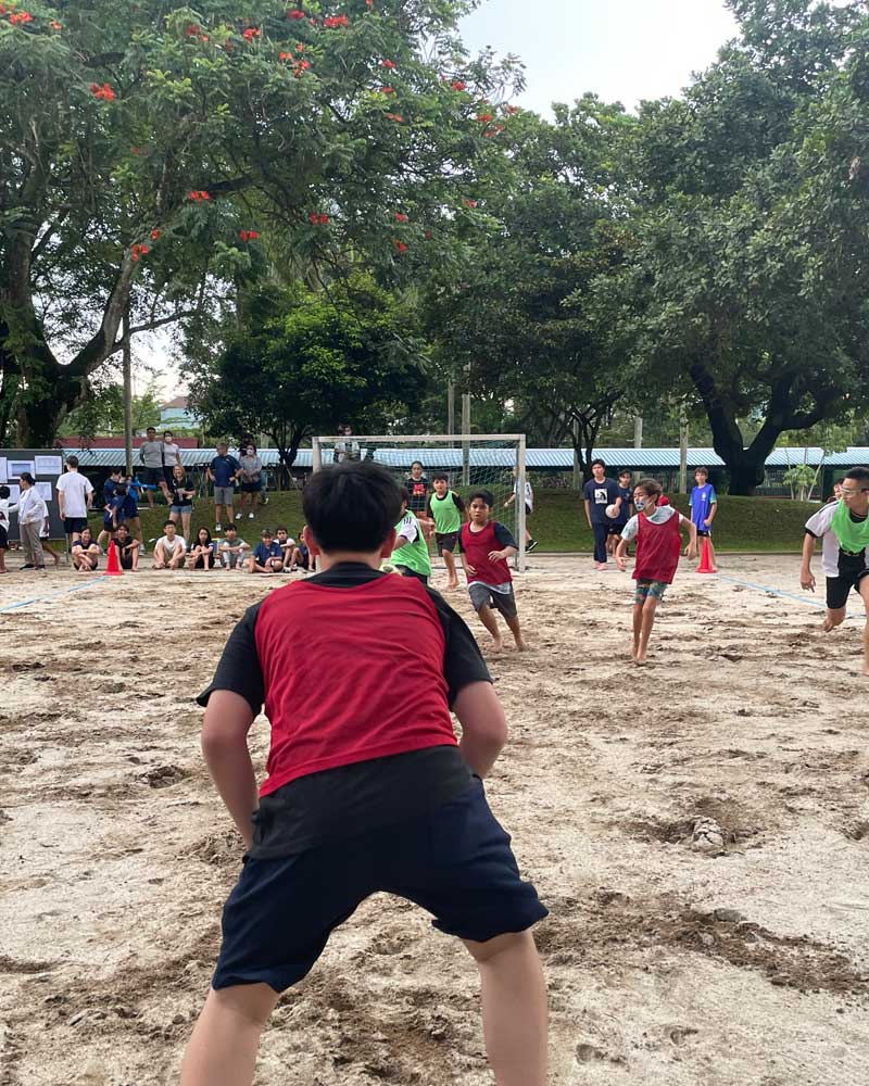 A boy in a red shirt is playing volleyball in the sand