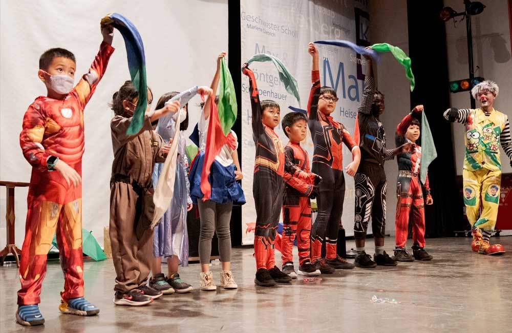 A group of children in costumes are standing on a stage.