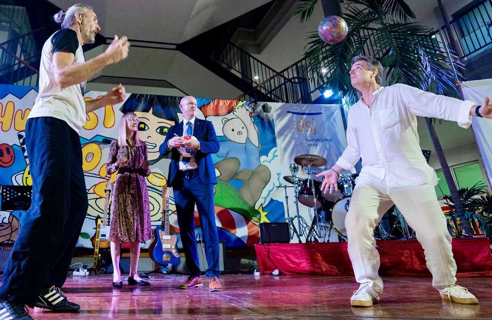 A group of people are standing on a stage playing with a ball.