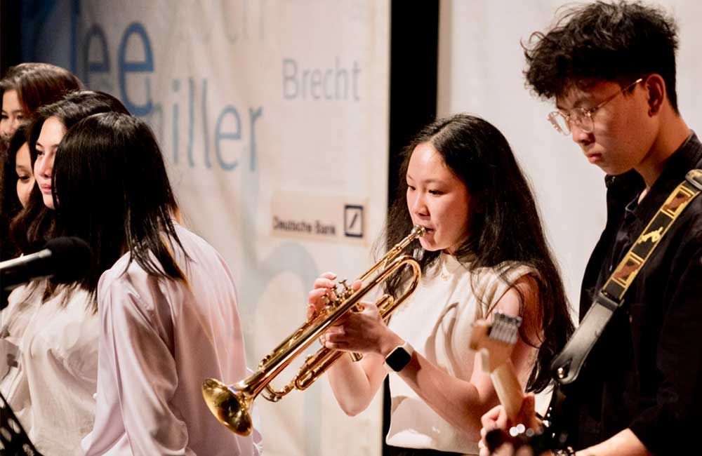 A group of people are playing instruments in front of a sign that says brecht