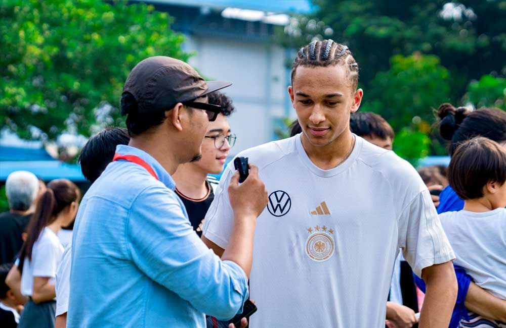 A man is taking a picture of a man in a white shirt.