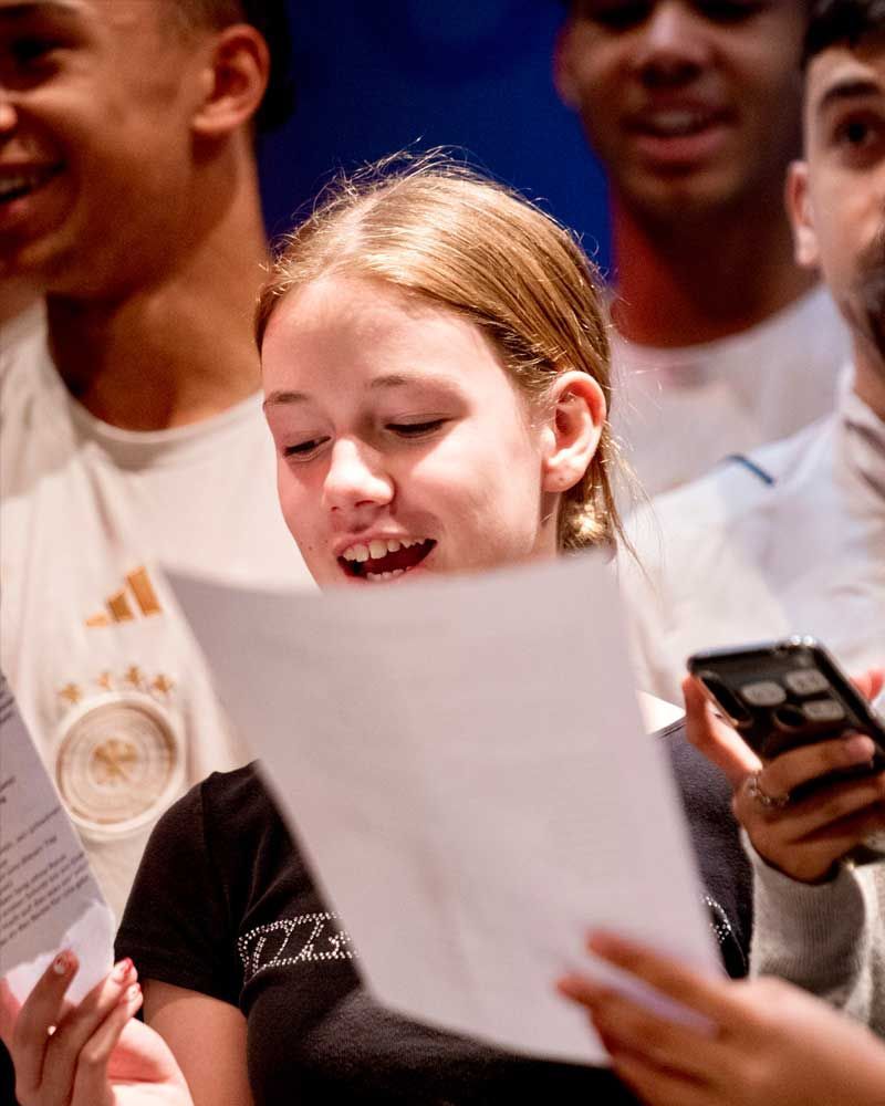 A girl is smiling while holding a piece of paper