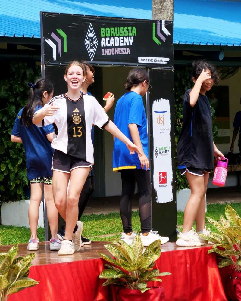 A group of girls are standing in front of a sign that says borussia academy indonesia