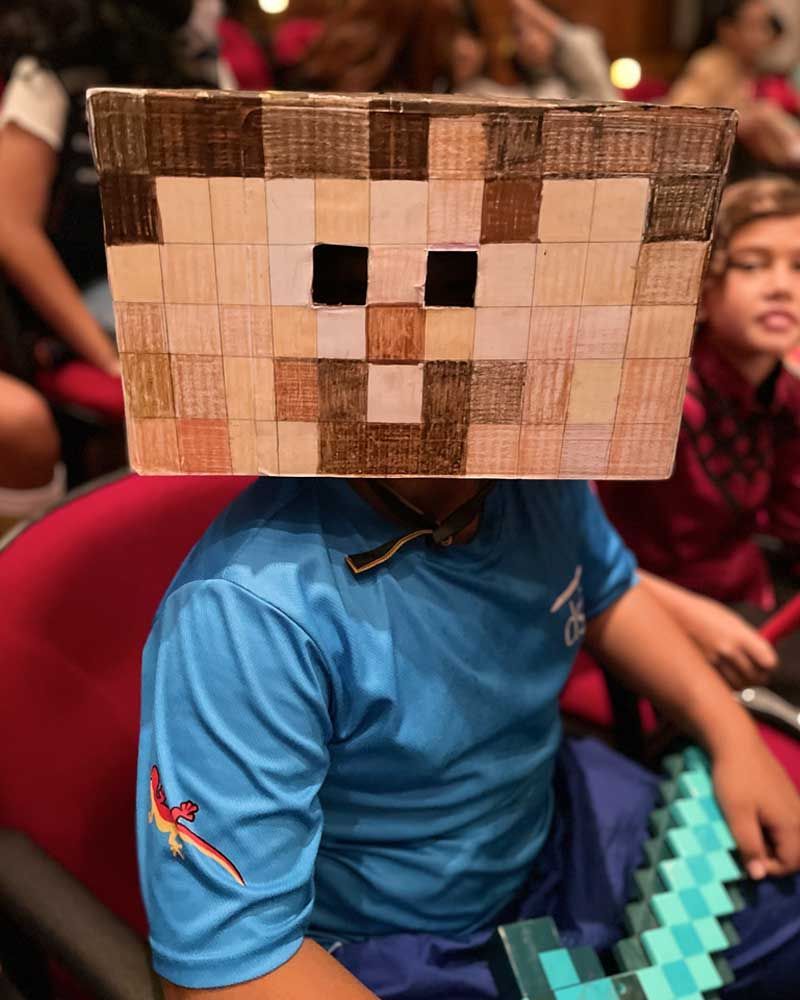 A child is wearing a minecraft mask on their head