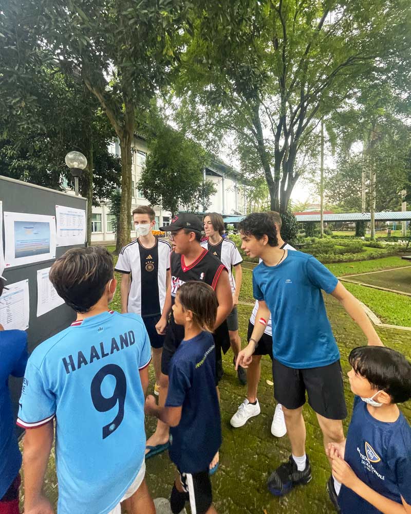 A group of young boys are standing in a park talking to each other.