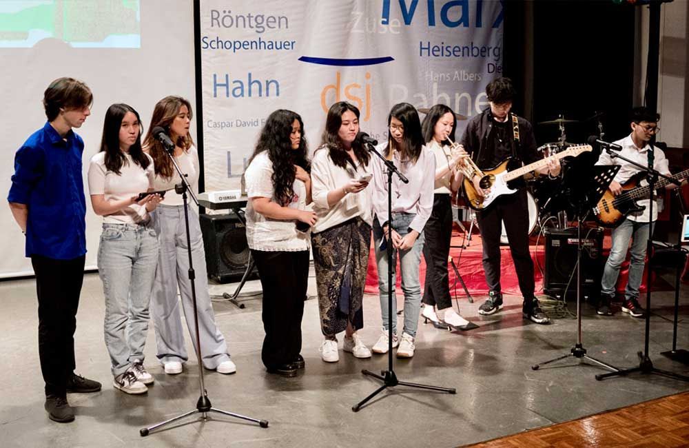 A group of young people are standing in front of microphones on a stage.