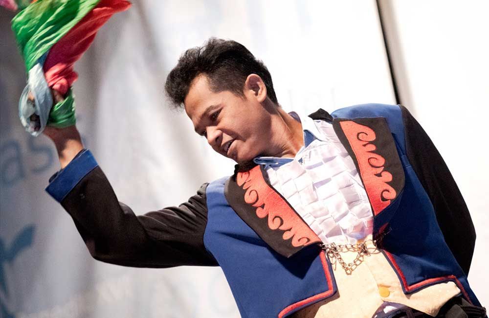 A man in a blue and black jacket is holding a rainbow flag