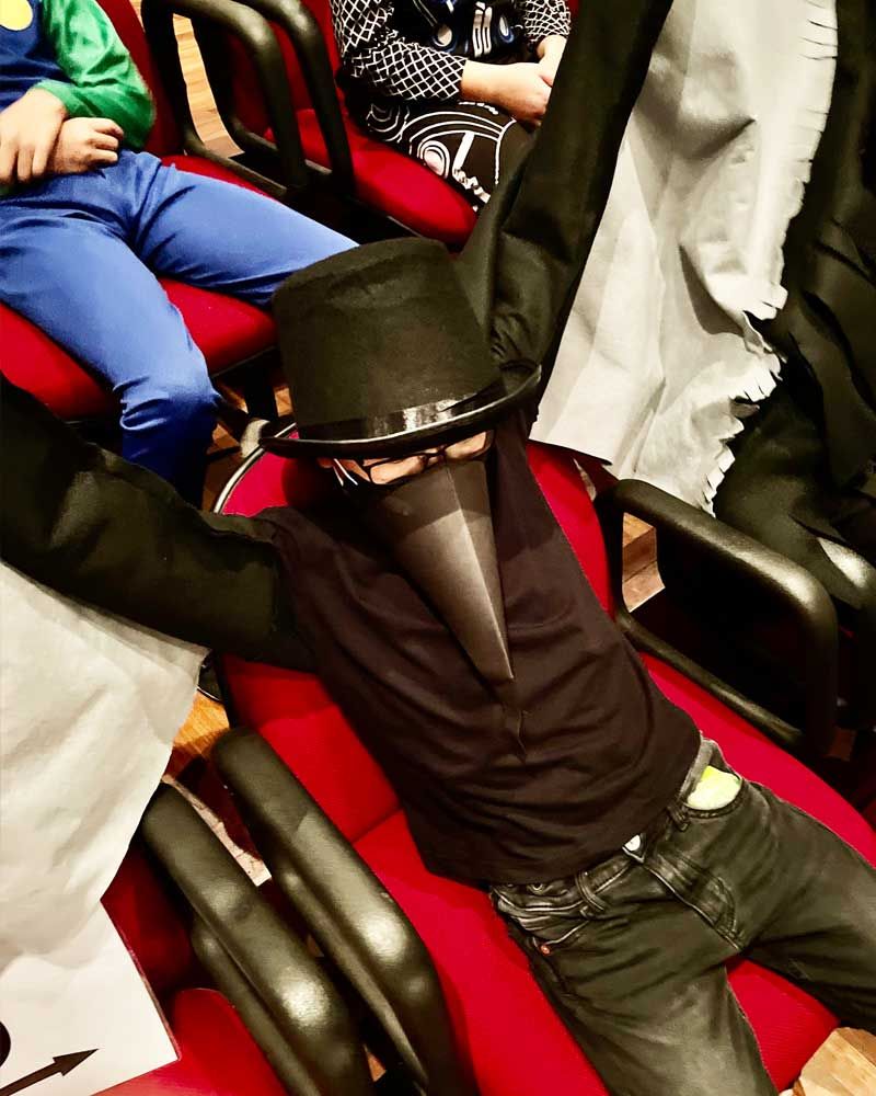 A man in a black hat and mask is laying on a red chair