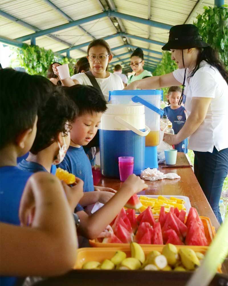 A woman is serving watermelon to a group of children