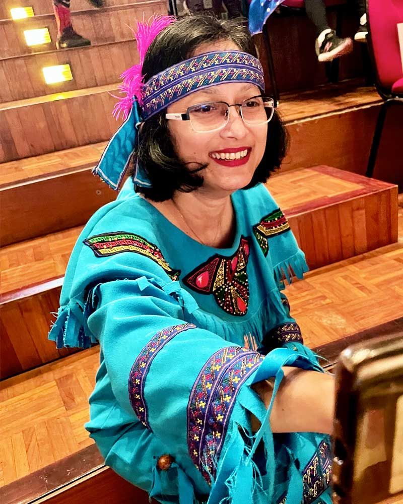 A woman in a blue dress and headband is sitting at a table.