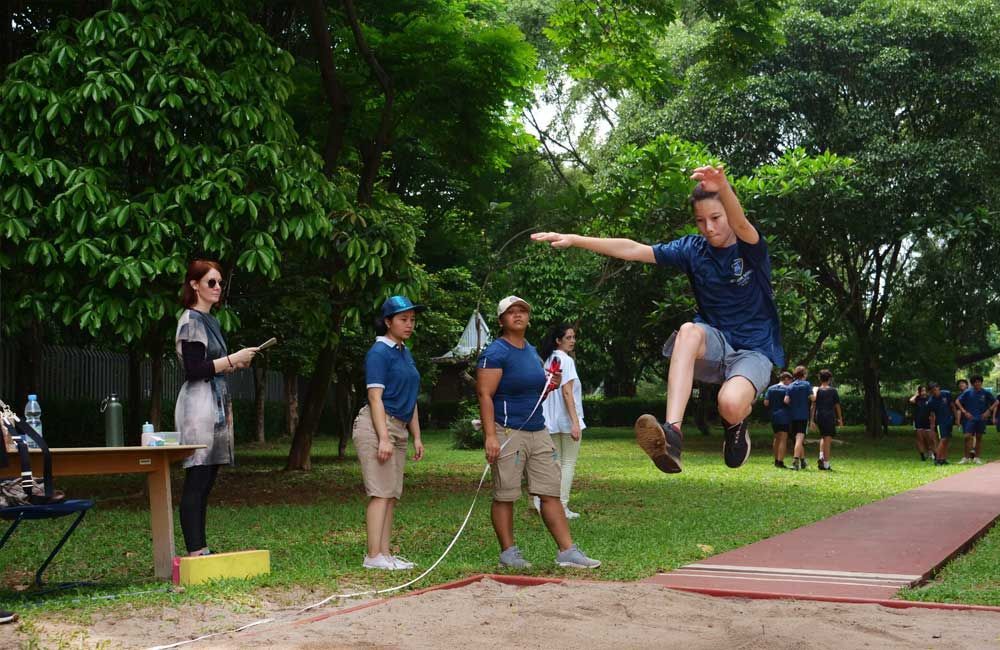 A person is jumping in the air while a group of people watch.