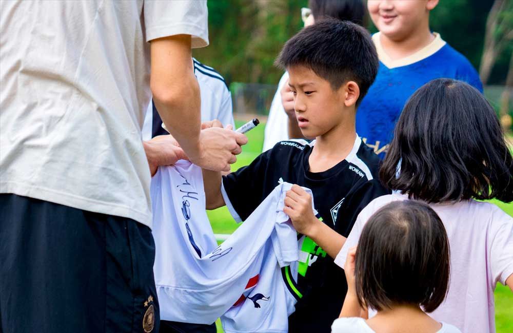 A group of children are standing around a man holding a white shirt.