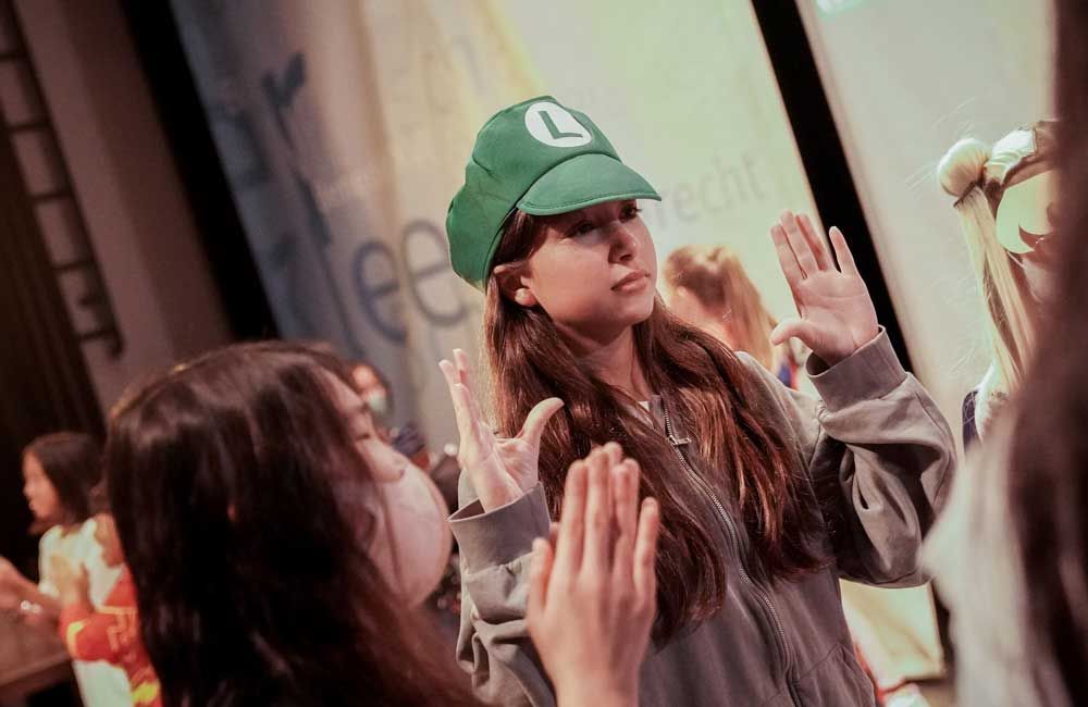 A girl wearing a green hat with the letter l on it.