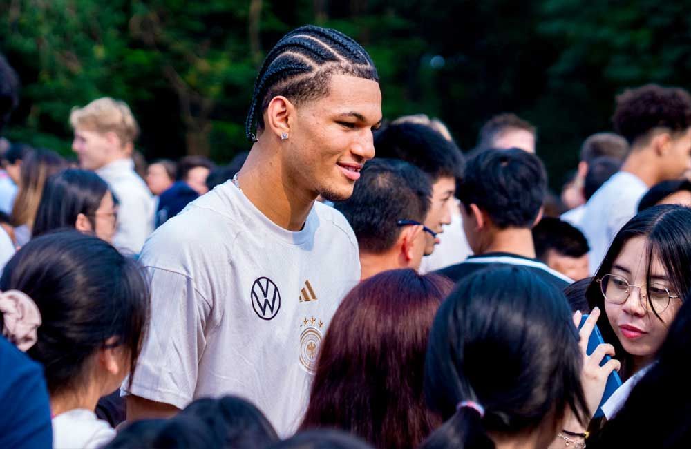 A man in a white shirt is standing in a crowd of people.