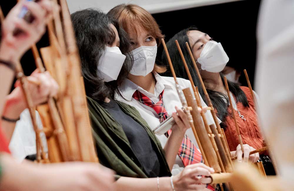 A group of young women wearing face masks are playing a musical instrument.