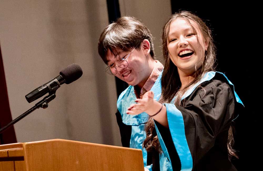 A man and a woman are standing at a podium with microphones.