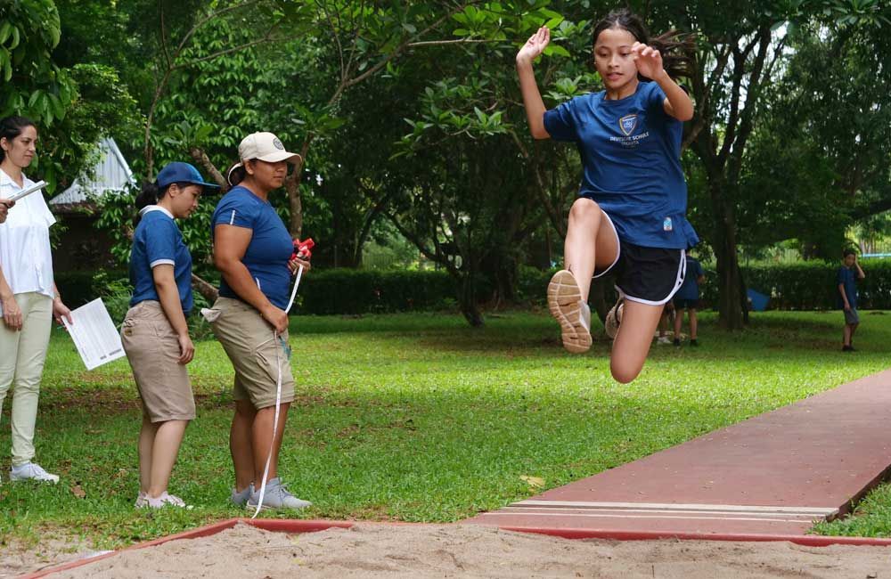 A girl is jumping in the air while a group of people watch.