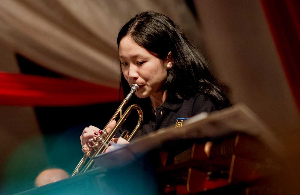 A woman is playing a trumpet in an orchestra.