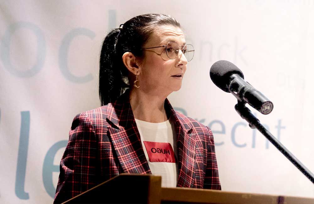 A woman is standing at a podium speaking into a microphone.