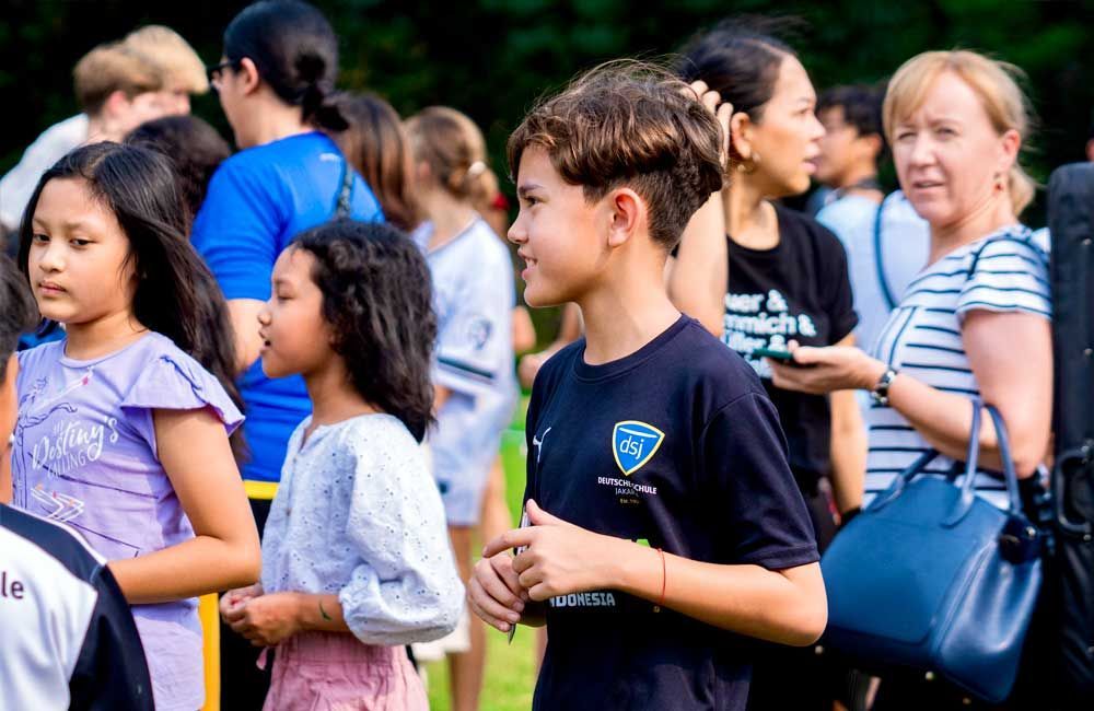 A group of people are standing in a line in a park.