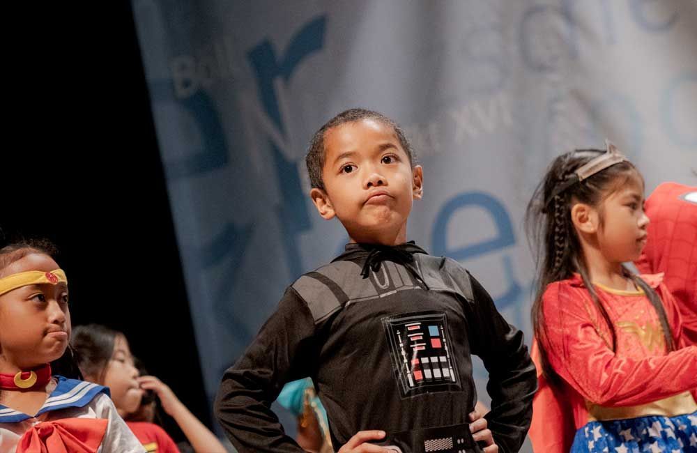 A group of young girls dressed in costumes are standing on a stage.