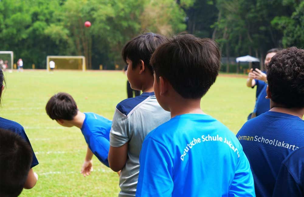 A boy wearing a blue shirt with the word schule on it