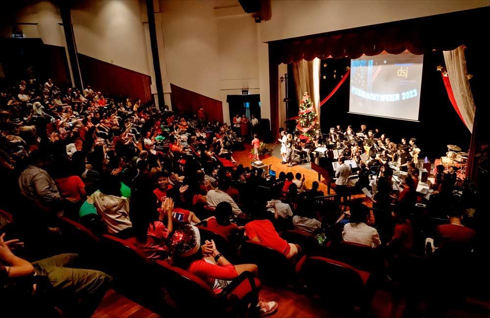 A large group of people are sitting in an auditorium watching a christmas concert