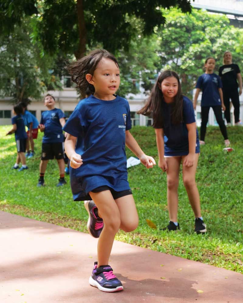 A group of children are running on a path in a park.