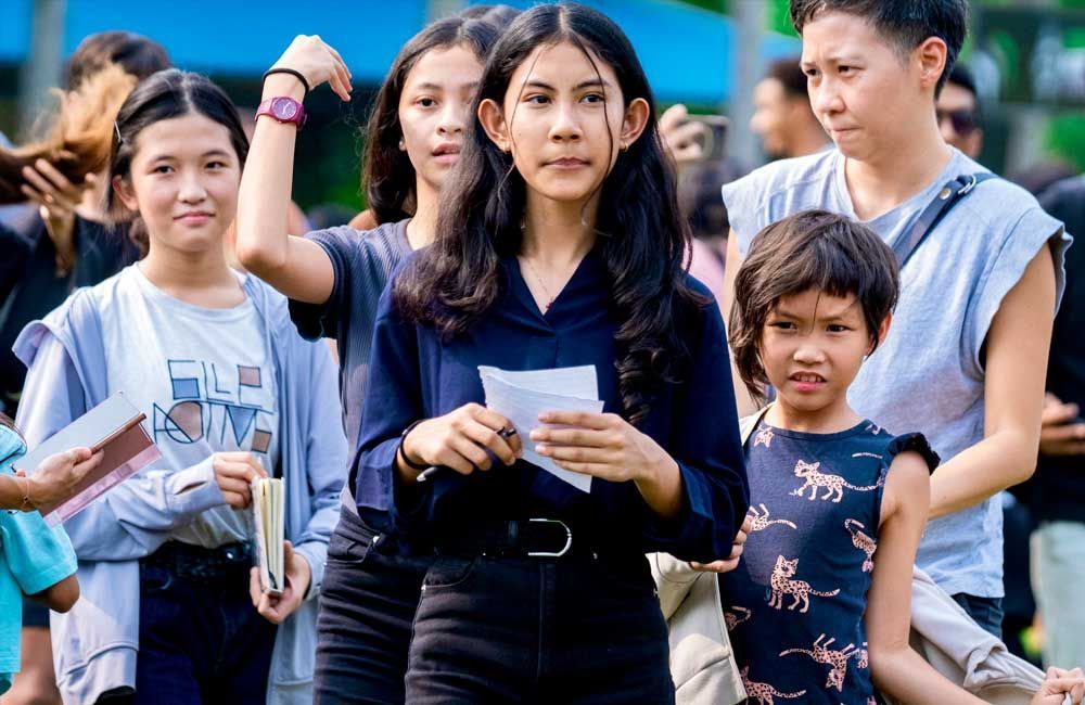A group of people are standing in a line holding papers.