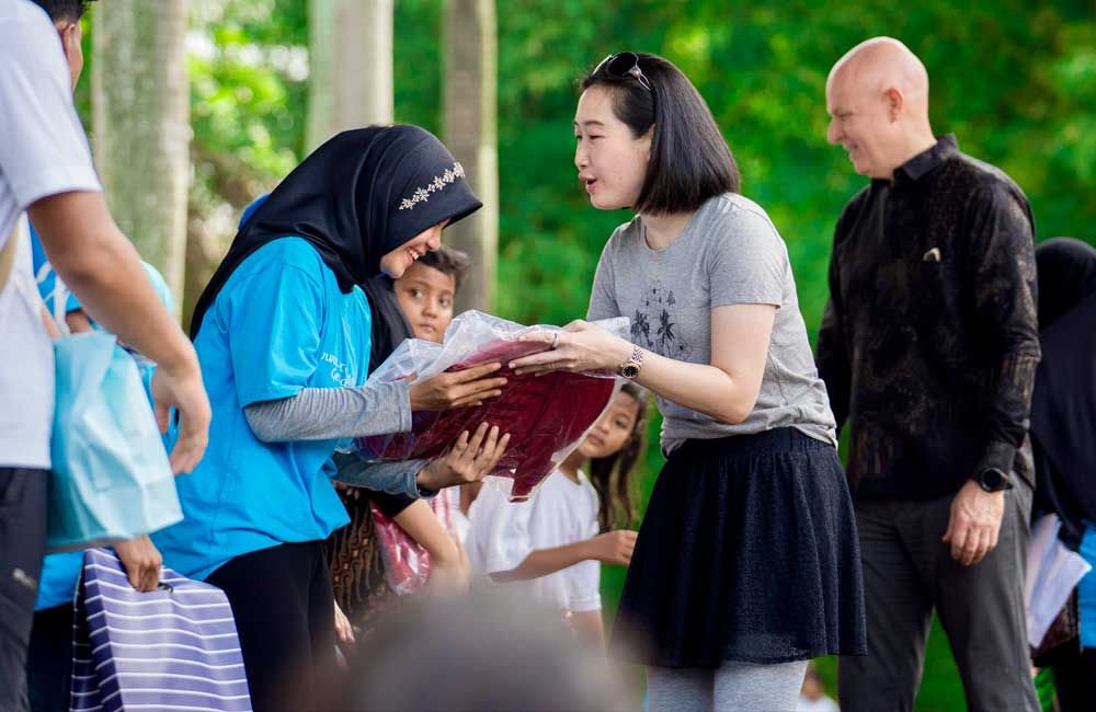 A group of people are standing around a woman holding a book.