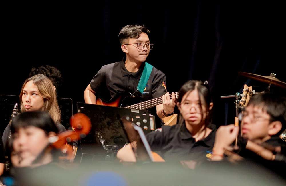 A man is playing a guitar in an orchestra.