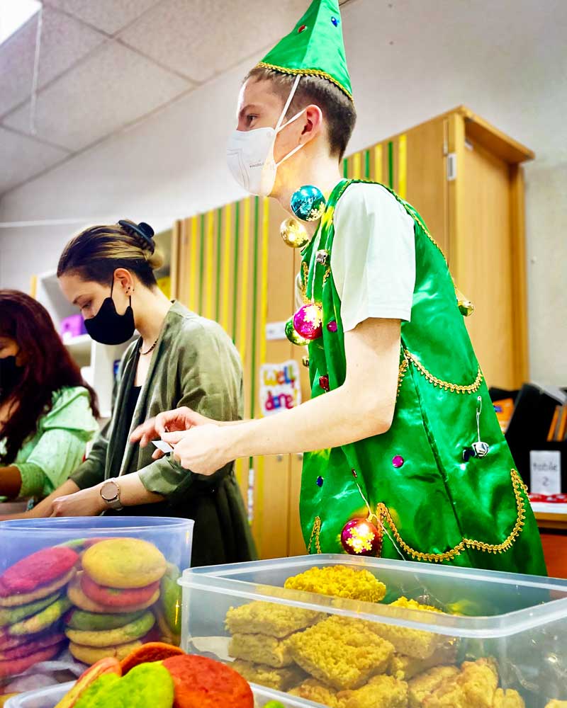 A man in a green elf costume is preparing food
