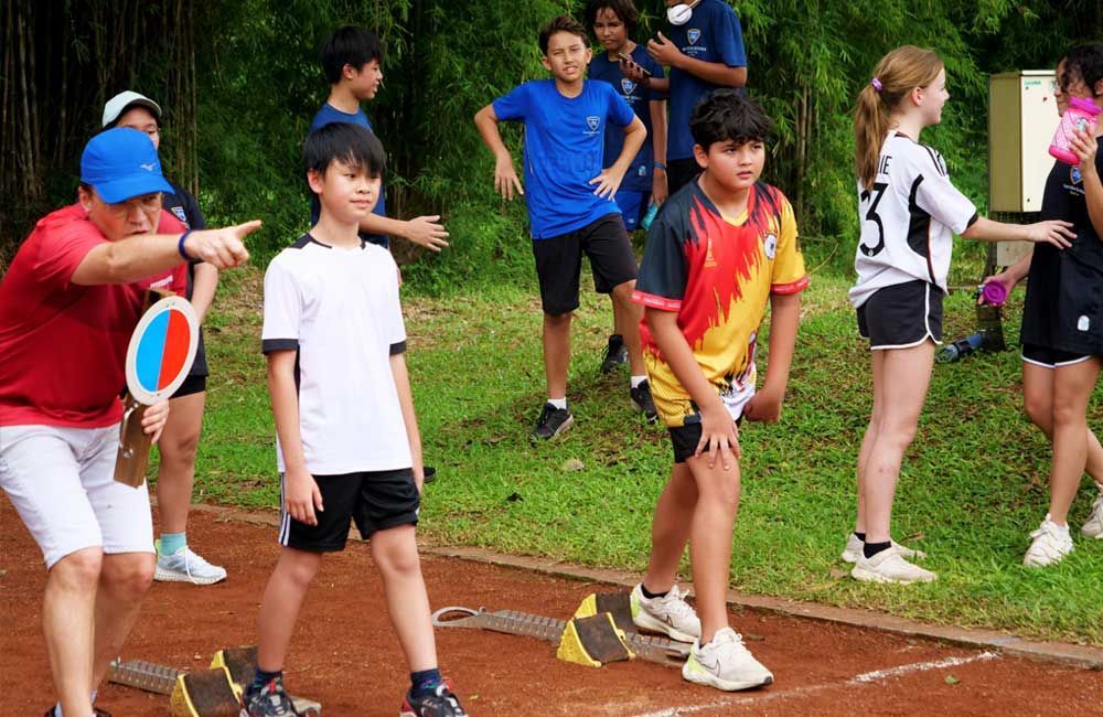 A group of children are standing on a dirt track.
