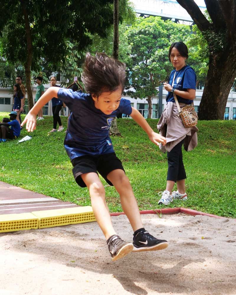 A young boy in a blue shirt is jumping in the air