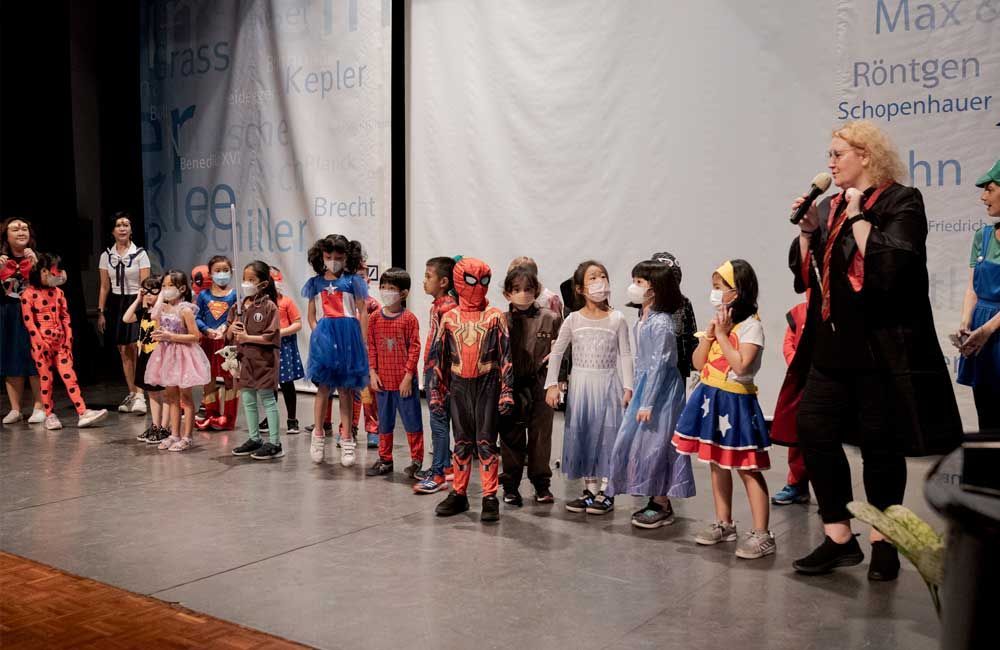 A group of children dressed in costumes are standing on a stage.