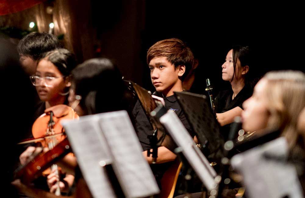 A group of young people are playing instruments in an orchestra.