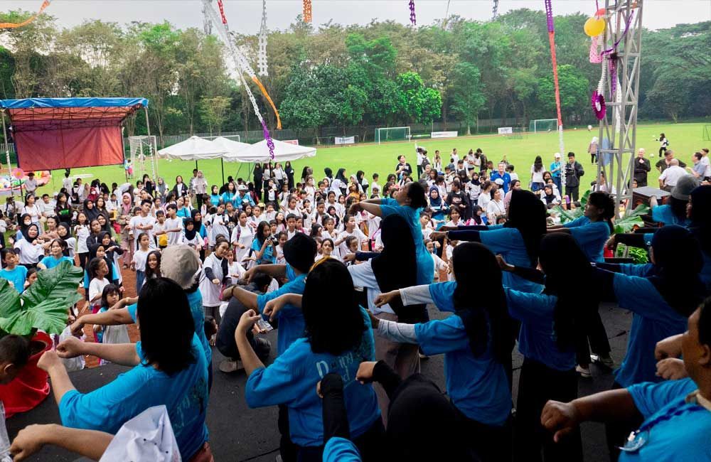 A large group of people are dancing in a field.